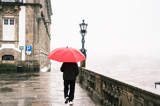 Porto, Portugal; November 20, 2022: A person with a red umbrella walking around the Porto Cathedral