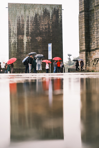 Porto, Portugal; November 20, 2022: Reflection with several people with umbrellas in the background at the Porto Cathedral