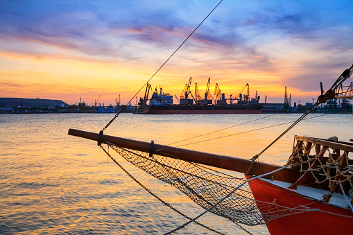 View of the port of Varna at sunset, moored sailing ship and harbor cranes in the background, on the Black Sea coast of Bulgaria