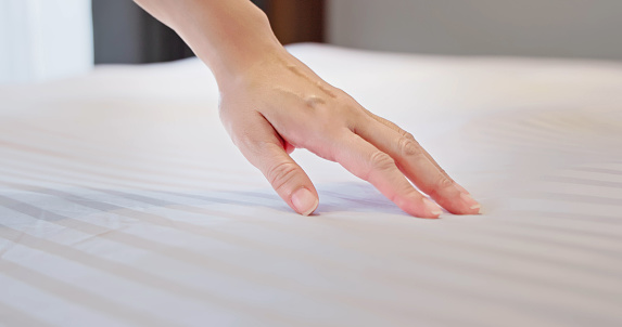 close up asian woman dragging her hand on clean white bed gently at home or in hotel - relaxing soft comfortable concept