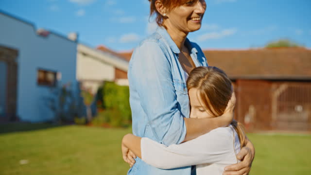 SLO MO Mother consoles her sad daughter on the lawn of their detached house