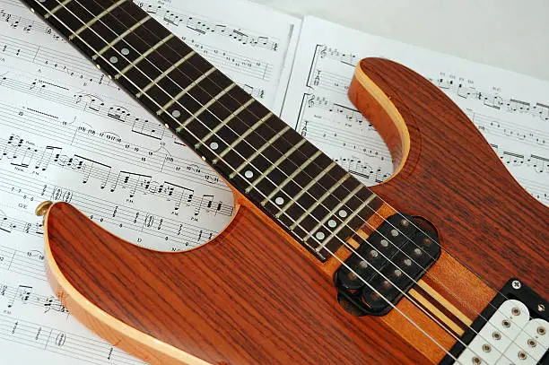 electric guitar laid over some sheet of music