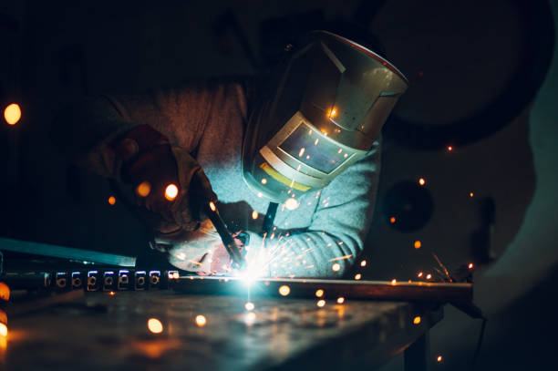 Man worker welding metal with welding machine in a factory or workshop Young male welder wearing construction gloves and welding mask hardworking and welding with welding machine metal in workshop. Copy space. Portrait of a worker in furniture factory grinding metal. grinding metal power work tool stock pictures, royalty-free photos & images