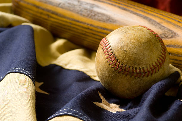 Antique Baseball Items vintage baseball items including a baseball and a bat, lying on top of vintage, antique American flag bunting. american flag bunting stock pictures, royalty-free photos & images