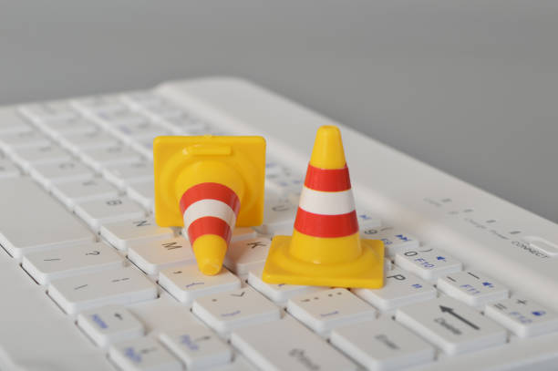 istock Traffic cones and laptop keyboard.Computer system under construction, repair and maintenance concept. 1443677335