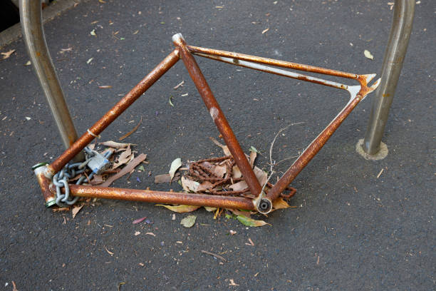 Looking down at a rusty bicycle frame chained to a bike rack.