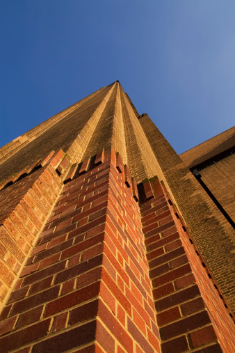 A Sunny day on the South Bank of London. An upward shot of the old power station that is now the Tate Modern art gallery along the Thames next to the Shakespeare's Globe theater. A blue sky and tall red brick building.