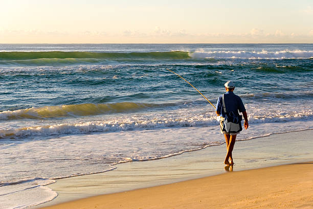 Costa da Caparica, Portugal - Mars 12, 2023: A surfer heads to the sea to catch some waves  in a beach in the Setúbal district, South of Portugal.