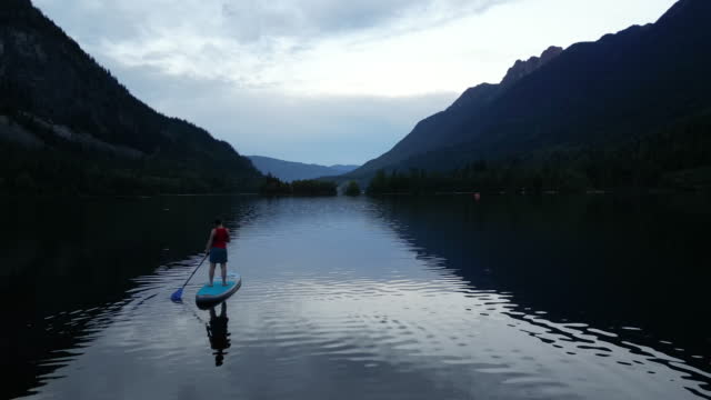 Aerial view of stand up paddle boarder (SUP) enjoying tranquil moments on lake