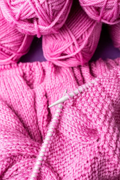 istock Background with knitting pink wool sweater in progress and yarn balls. top view. Knit a Braid Cable 1443686880