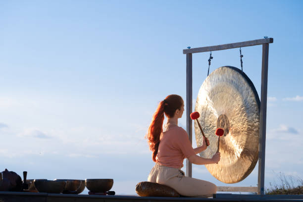 istock Music therapy, woman playing bronze gong, back side view 1443687132