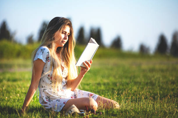 istock beautiful young woman reading a book in the public park at sunset 1443700708