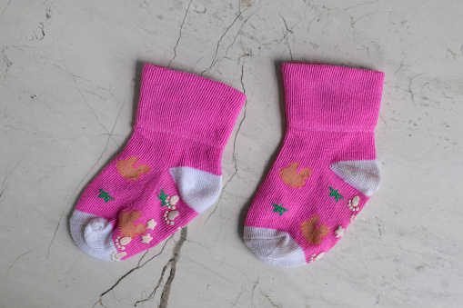 Pair of small baby socks on ceramic background. Pink baby socks