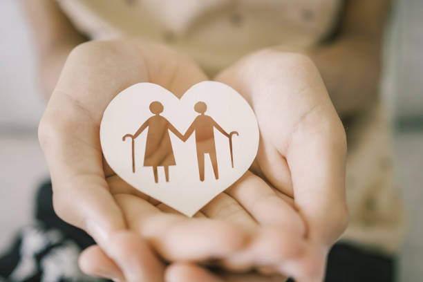Teen hands holding elderly couple with walking sticks in heart shape, older people mental health, age care concept stock photo