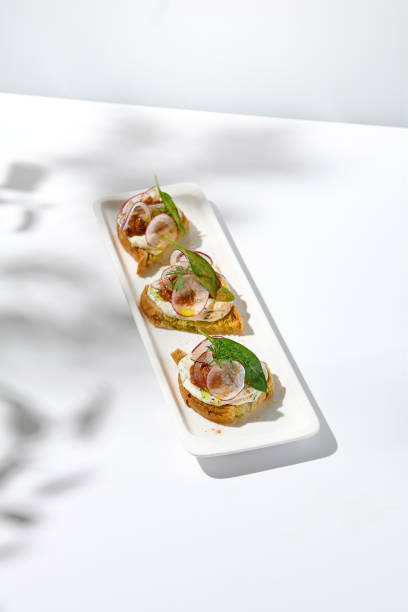 istock Aesthetic composition with tomato bruschetta on white background with harsh shadows. Italian bruschetta with tomatoes and cheese on fine dining in summer. Elegant menu concept. 1443731101