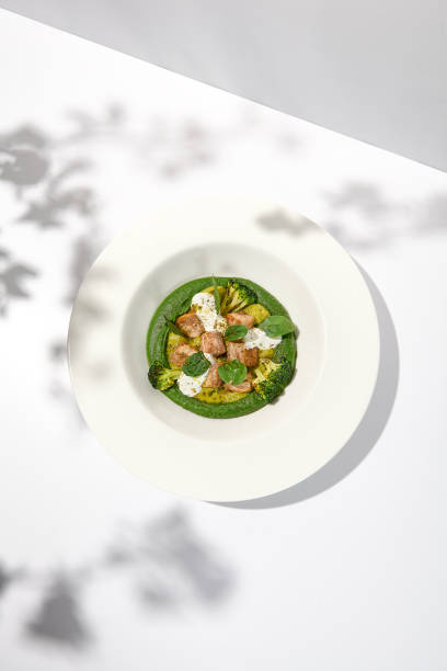 istock Creative dish from roasted chicken and broccoli puree on white plate. Sliced baked chicken with vegetables and creamy espuma in summer menu. 1443731205