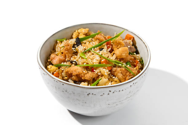 Fried rice with egg, chicken and vegetables isolated on white background. Traditional chinese food - fried rice with chicken meat in ceramic bowl Nasi goreng with fried rice, chicken and egg Fried rice with egg, chicken and vegetables isolated on white background. Traditional chinese food - fried rice with chicken meat in ceramic bowl. Nasi goreng with fried rice, chicken and egg chinese cuisine fried rice asian cuisine wok stock pictures, royalty-free photos & images