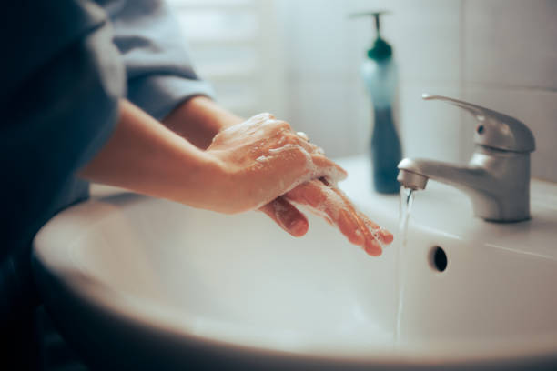 Person Washing her Hands with Soap in the Sink stock photo