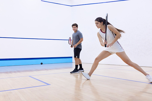 Squash player running to hit the ball
