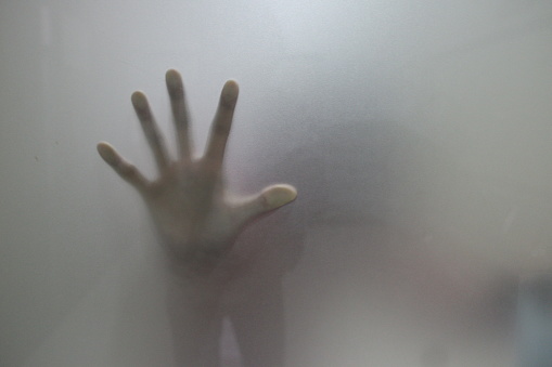 Hand silhouette behind glass
