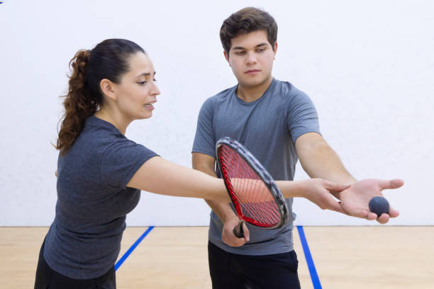 entrenador instruyendo a su aprendiz sobre cómo recoger la raqueta y la pelota para servir. - squash racketball sport exercising fotografías e imágenes de stock