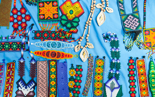 An array of colourful handmade jewellery is seen displayed on a sky blue cloth.