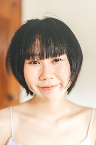 Portrait of young adult asian woman after self care. Hair bangs cut on face. Authentic candid people and asia skin. Wellness mental health lifestyle concept. Eye looking at camera.