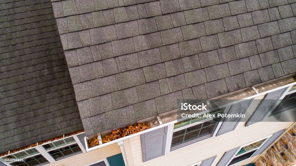 Inspection of roof shingles and gutters from drone in autumn. Drone inspection of roof shingles and gutters in autumn. Roof Gutter Stock Photo