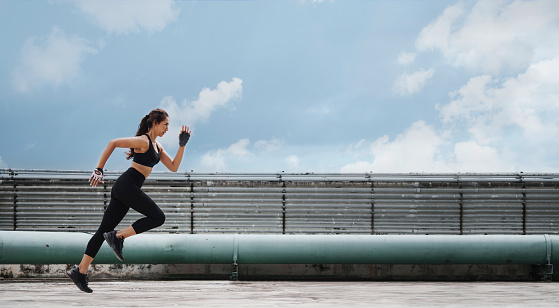 Woman athlete doing running and lunge exercise workout on rooftop.