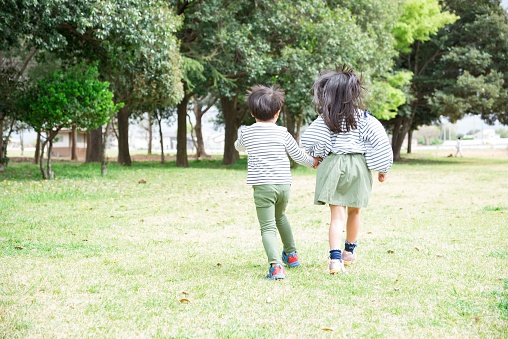 Asian children walking hand in hand in a park full of nature
