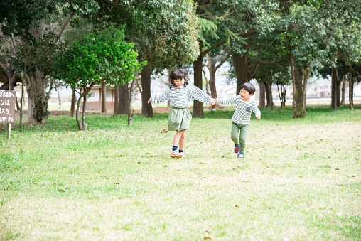Asian children walking hand in hand in a park full of nature