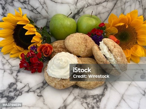 istock Closeup shot of Sugar cookies, sunflowers and two Granny Smith on marble surface 1443764034