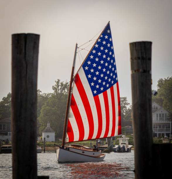 istock Catboat with an American Flag sail in a harbor 1443764353