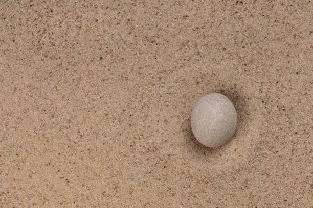 White stone on sand for relaxation balance and harmony spirituality or wellness spa. Top view.