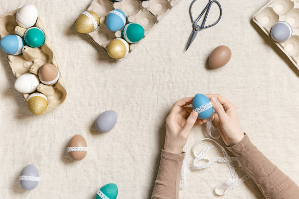 istock Decoration colored Easter eggs, prepare for Happy Easter celebration, woman decorating dyed chicken egg with tape lace on table linen Lifestyle aesthetic photo at home, diy holiday 1443771507
