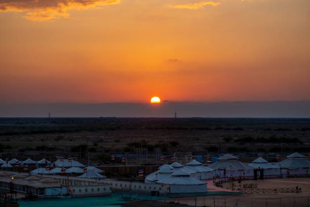 istock Beautiful sunset scene with orange sky on large fields with huge tents and flags 1443771737