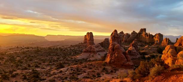 istock Panoramic view of rock formations in a desert covered with shrubs at sunset in Arches National Park 1443772084