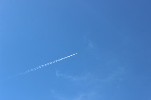 The airplane flying in the blue sky leaving contrails from behind