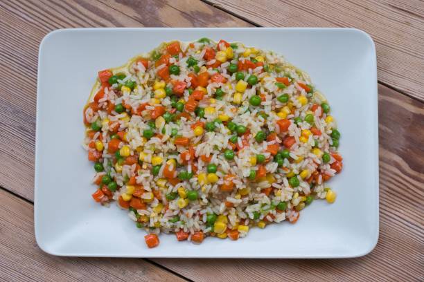 istock Risotto, with corn, carrot and peas on a wooden table. 1443773484