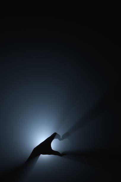 A heart shape with hands in rays of bright light.