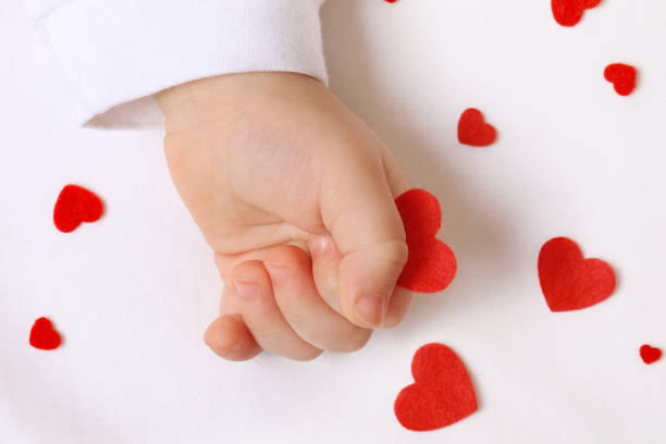 istock Infant Hand and Red Hearts 1443776455