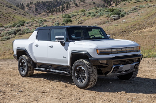 – May 26, 2022: A 2022 GMC Hummer EV in white sits atop a dirt road in the rural backcountry hills.