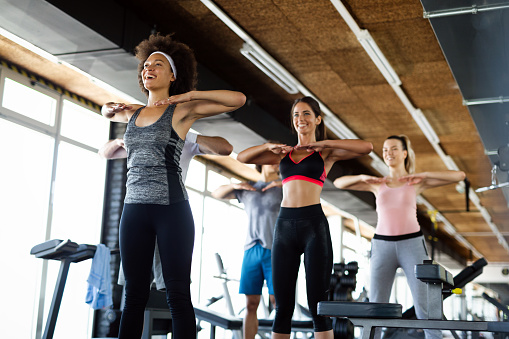 Group of sportive fit people working out in a gym. Multiracial friends exercising together in fitness club.