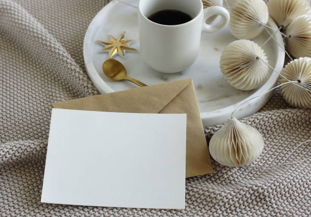 istock Blank greeting card, invitation mock up, craft envelope,beige knitting blanket, Christmas tree decorations in marble tray  and cup coffee.Xmas  scene  stationery still life neutral colors.Copy space 1443788822