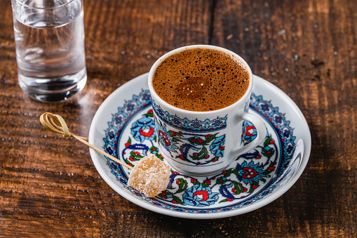 Turkish coffee in classic coffee cup with water and Turkish delight on wooden table