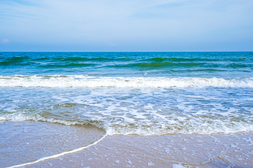 Light blue sea waves on a clean sandy beach.