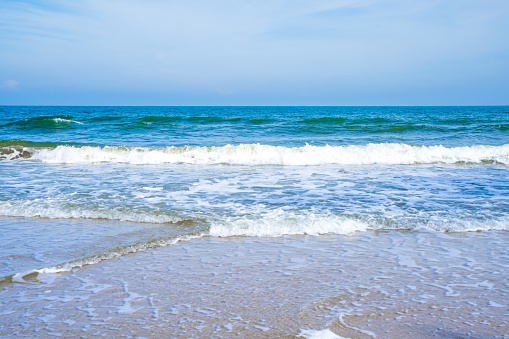 Light blue sea waves on a clean sandy beach.