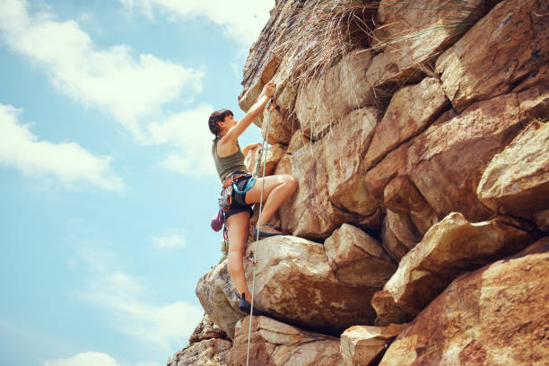 une femme dans la nature escalade, entraînement et fitness en plein air par une journée ensoleillée avec du matériel d’escalade. une athlète féminine, forte et en bonne santé qui fait de l’exercice, de l’activité physique et de l’escalade e - rock climbing mountain climbing women achievement photos et images de collection