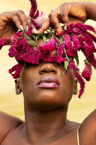 Beautiful African woman holding flowers in front of her eyes
