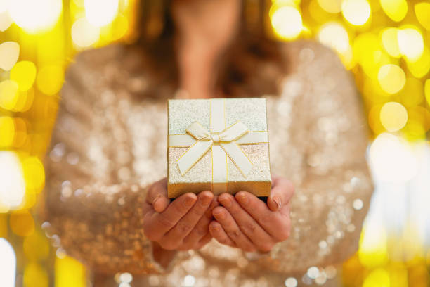 istock Young woman with gift over gold background 1443797775